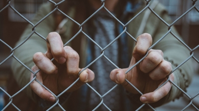 person's hands on chain link fence